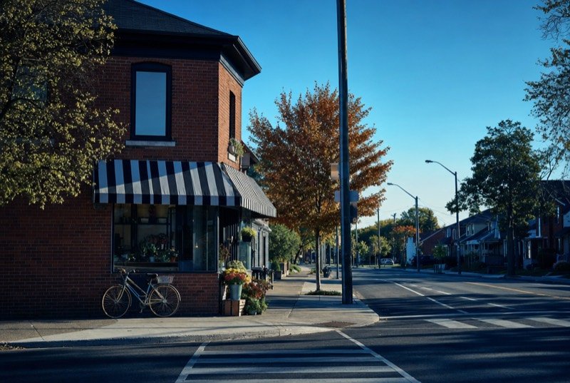 A red-brick corner storefront under a striped awning, a bike leaning out front